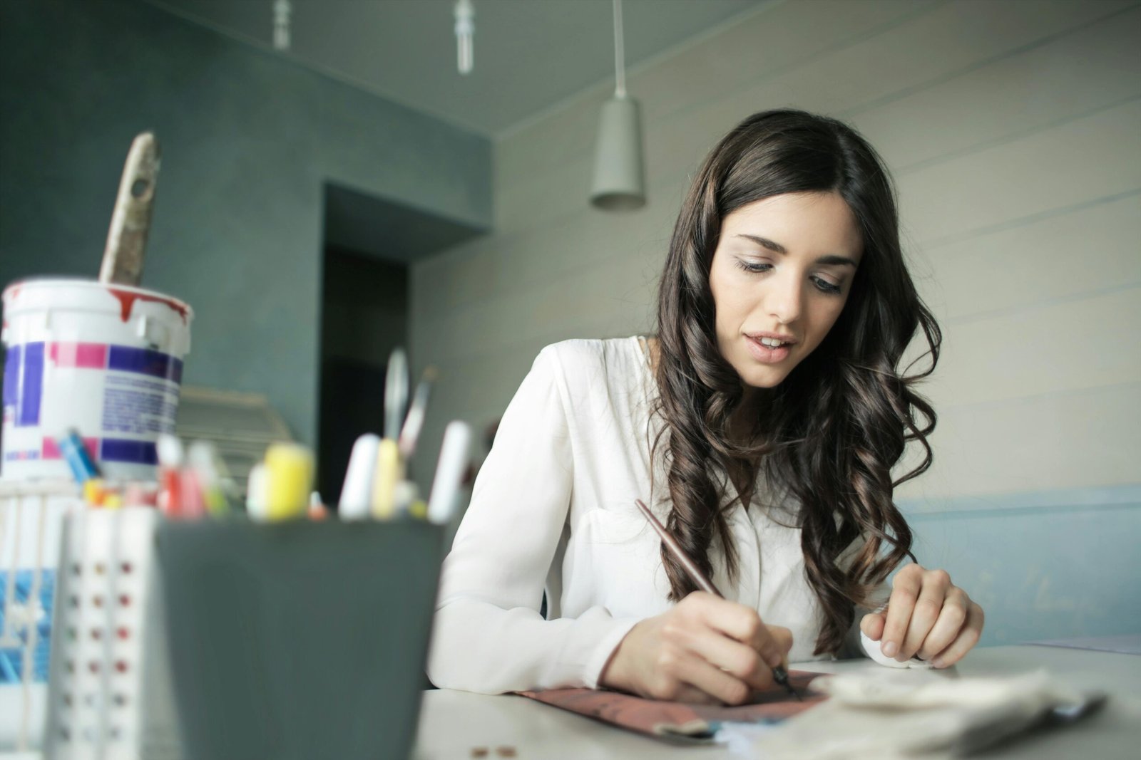 Young woman artist focused on painting at her workspace.