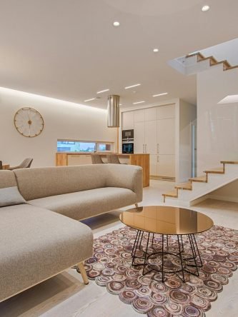 Contemporary living room with neutral tones, a sleek sofa, and elegant wooden staircase.